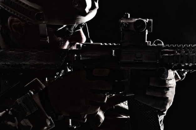 contour backlight portrait of special forces soldier in uniforms pointing weapons, closeup portrait on black