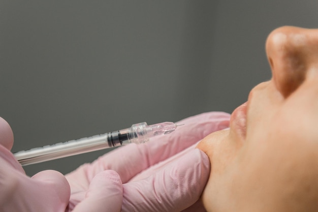 Contourplastiek Een schoonheidsspecialist injecteert een botulinumtoxine om rimpels op de huid van een vrouwelijk gezicht strakker en gladder te maken