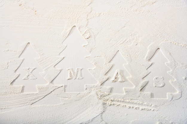 Contours of decorative Christmas trees and letters on flour