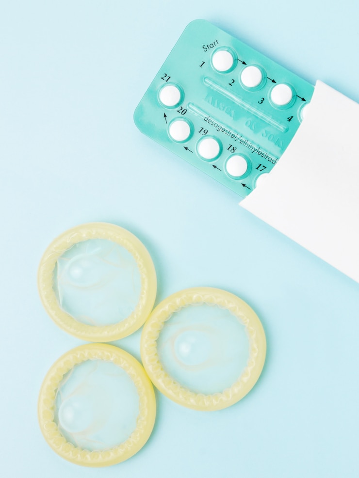 Photo contraceptive pills and condoms on blue 