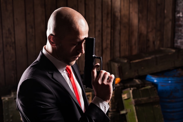 Contract assassin in suit and red tie holds gun.