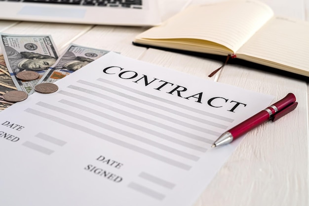 Photo contract with pen and dollar bills lie on a wooden table