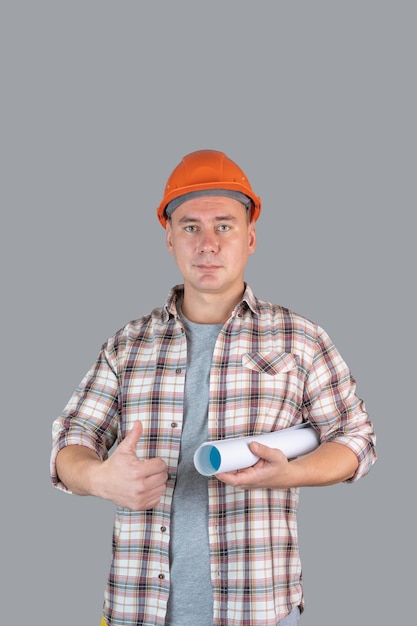 A contractor engineer in an orange helmet shows a thumbs up holding a roll with drawings