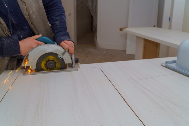 Contractor uses a saw to cut through a laminate kitchen formica countertop