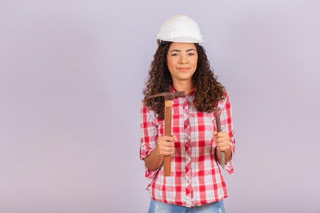 Contractor woman holding a hammer and cleaver.