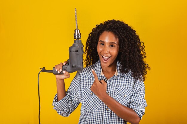 Contractor woman with a drill smiling at the camera