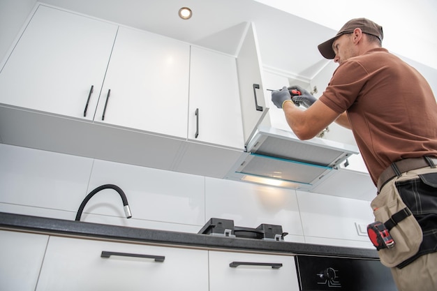 Photo contractor worker assembling of new apartment kitchen cabinets