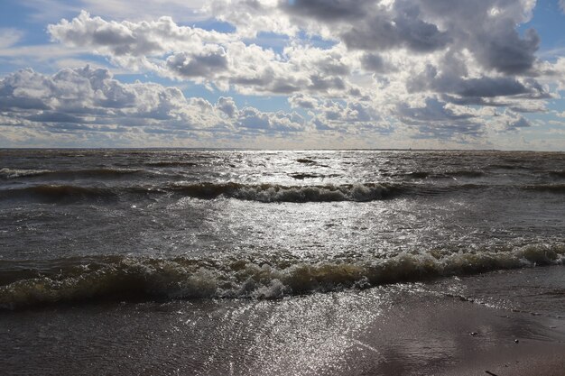 Contrast blauwe lucht met wolken boven de zee en een zonnig pad op het water