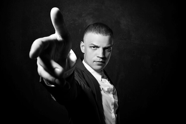 Contrast portrait of a man businessman in an expensive business suit. Manager businessman posing gestures with his hands on black