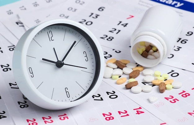 Control Time to take pills. Clock with a bottle of pills on a monthly calendar