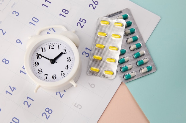 Control Time to take pills. Clock with pills on a monthly calendar.