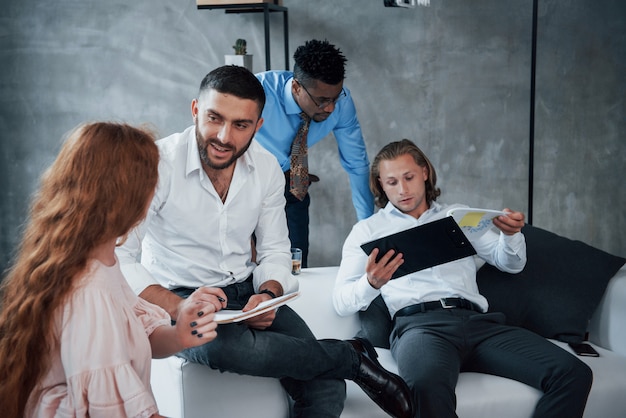 Controle van documenten. Groep multiraciale kantoorpersoneel in formele kleding praten over taken en plannen