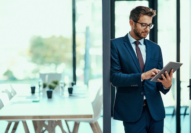 Foto controllare la propria attività con un semplice tocco inquadratura di un giovane uomo d'affari che utilizza una tavoletta digitale in un ufficio