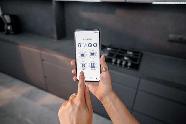 Foto controllo di dispositivi intelligenti con il telefono in cucina