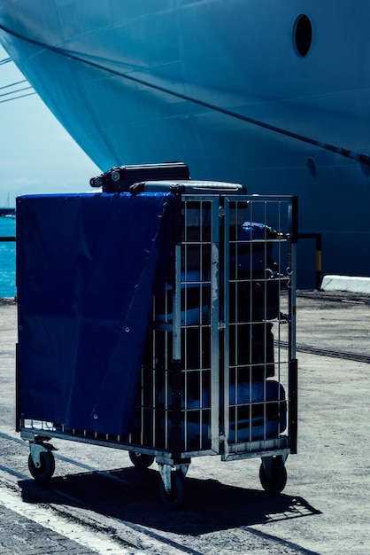 Foto un comodo carrello per trasportare i bagagli accanto a una nave da crociera ormeggiata
