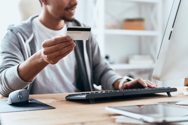 Convenient shopping. Close up of young man in casual clothing making a purchase online while spending time at home