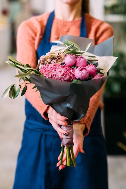 Comoda consegna di bouquet di fiori per qualcuno che ami. mani di donne che tengono una disposizione creativa di peonie e ortensie