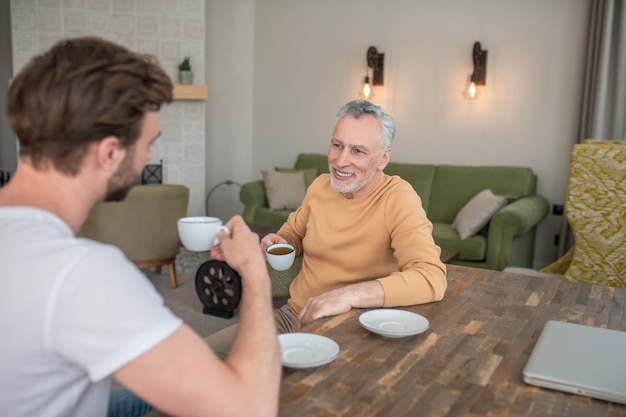 会話。テーブルに座ってお茶を飲みながら話している2人の男性