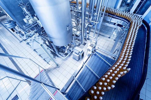 Photo conveyor belt with bottles for juice or water at a modern beverage plant