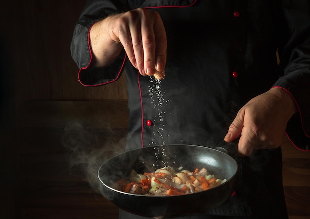 料理人が熱々の鍋に塩を加える 広告スペースのあるホテルのメニュー アイデア アジアの郷土料理 レストランのメニューまたはレシピ コピー スペース