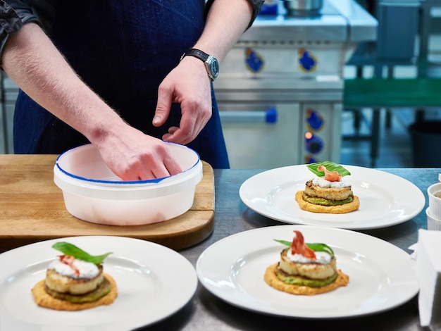 Cook are served dish with fish cutlet in restaurant