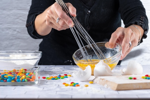 Cook beating eggs with ingredients and cooking tools around