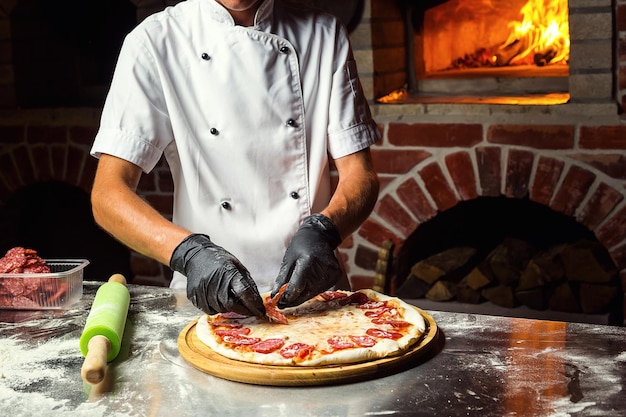 Cook Chef making delicious pizza at the restaurant closeup