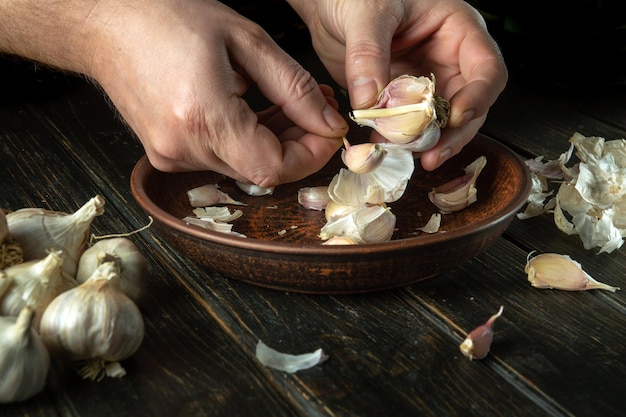 The cook cleans the garlic in a vintage plate on the kitchen table