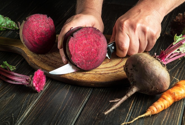 The cook cuts beetroot with a knife to prepare delicious borscht Ukrainian national cuisine