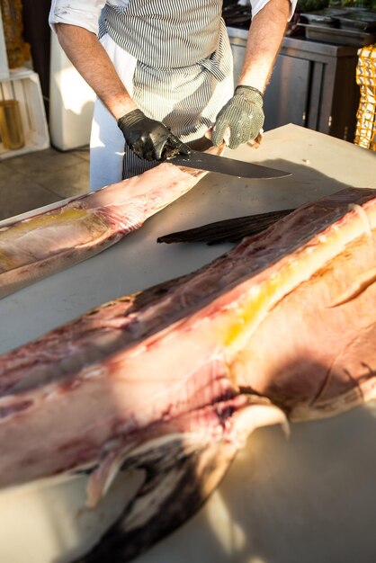 A cook cuts a big fish to a pieces in restaurant