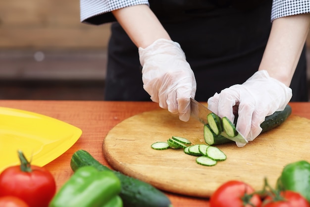 The cook cuts fresh farm vegetables for dinner on the table