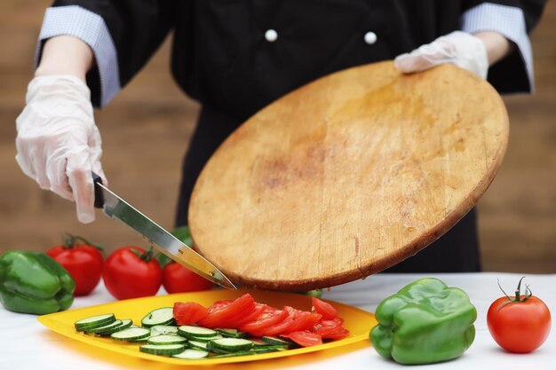 The cook cuts fresh farm vegetables for dinner on the table