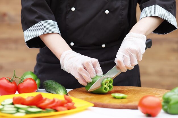 The cook cuts fresh farm vegetables for dinner on the table