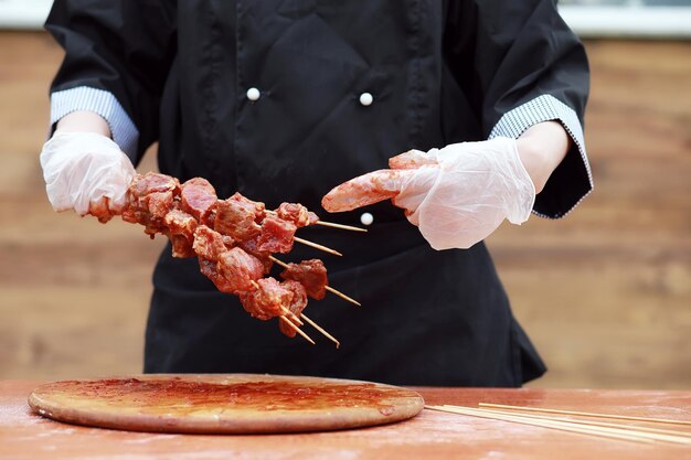 Foto il cuoco taglia la carne per cucinare il barbecue sul tavolo