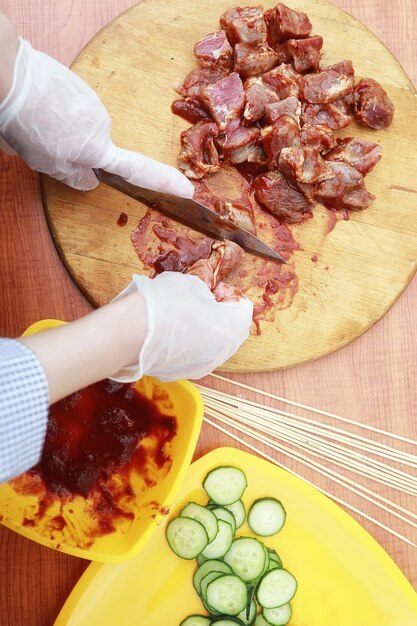 The cook cuts meat for cooking barbecue on the table