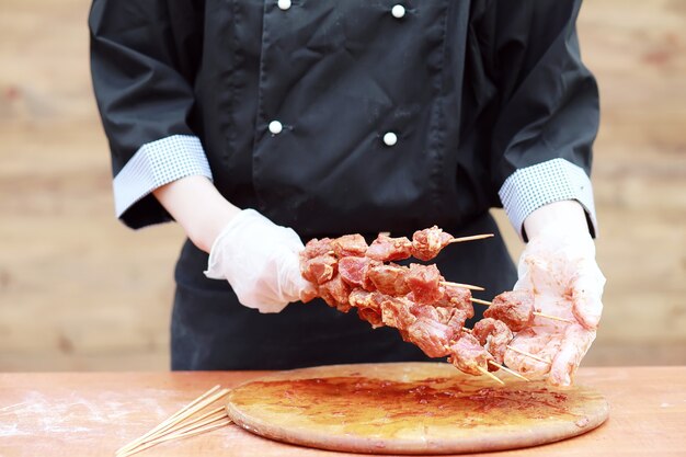 The cook cuts meat for cooking barbecue on the table