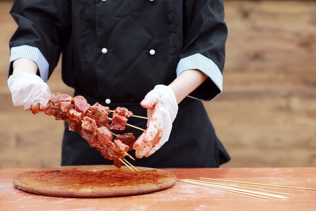 The cook cuts meat for cooking barbecue on the table