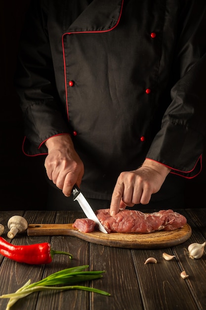 The cook cuts raw beef meat on a cutting board before baking Asian cuisine Hotel menu recipe idea