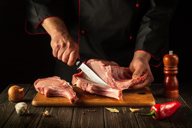 The cook cuts raw ribs on a cutting board before barbecuing