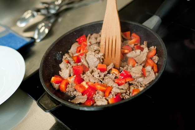 Cook fries meat in a pan with vegetables