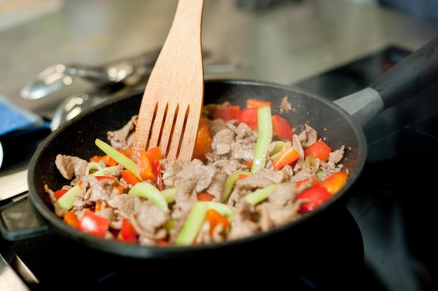 Cook fries meat in a pan with vegetables