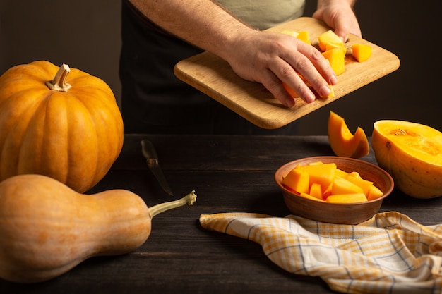 Cook gooit plakjes pompoen van een snijplank in een diepe kom.