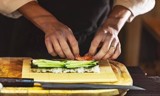 Cook hands making Japanese sushi roll