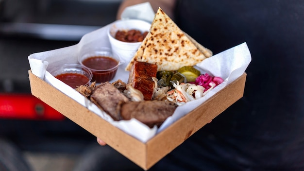 Photo cook holding dish with meal. meat and toppings. bbq. street food