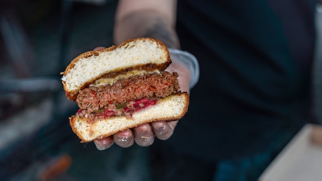 Cook holding finished sliced burger, BBQ. Street Food