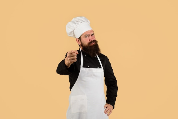 수염을 가진 요리사 모자 앞치마를 입은 전문 요리사 남자를 가리키는 제복을 입은 요리