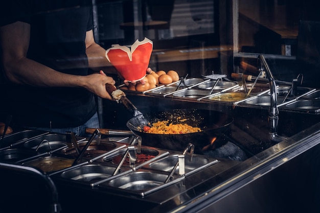 Cook is bak groenten met kruiden en saus in een wok. Kookproces in een Aziatisch restaurant.