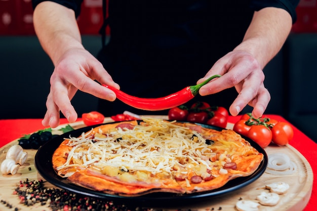 The cook is making pizza. Adds the ingredients.