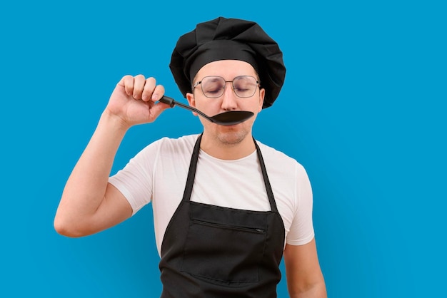 The cook is tasting food from a spoon on a blue background cooking and people concept