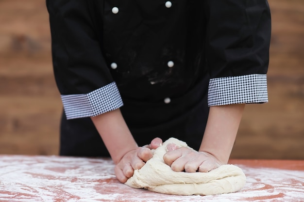 The cook makes flour out of flour for baking on the table